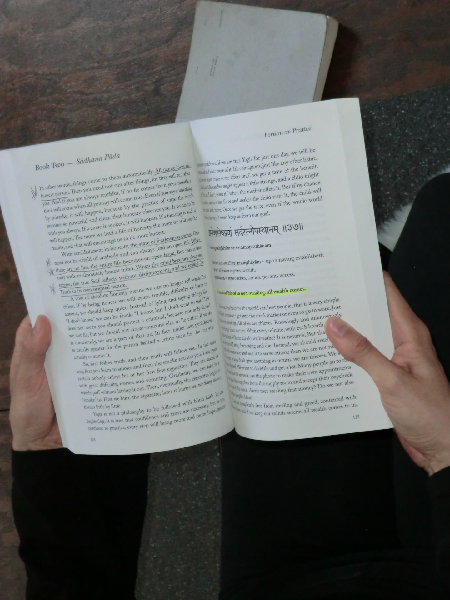 hands holding an open book on the yoga sutras
