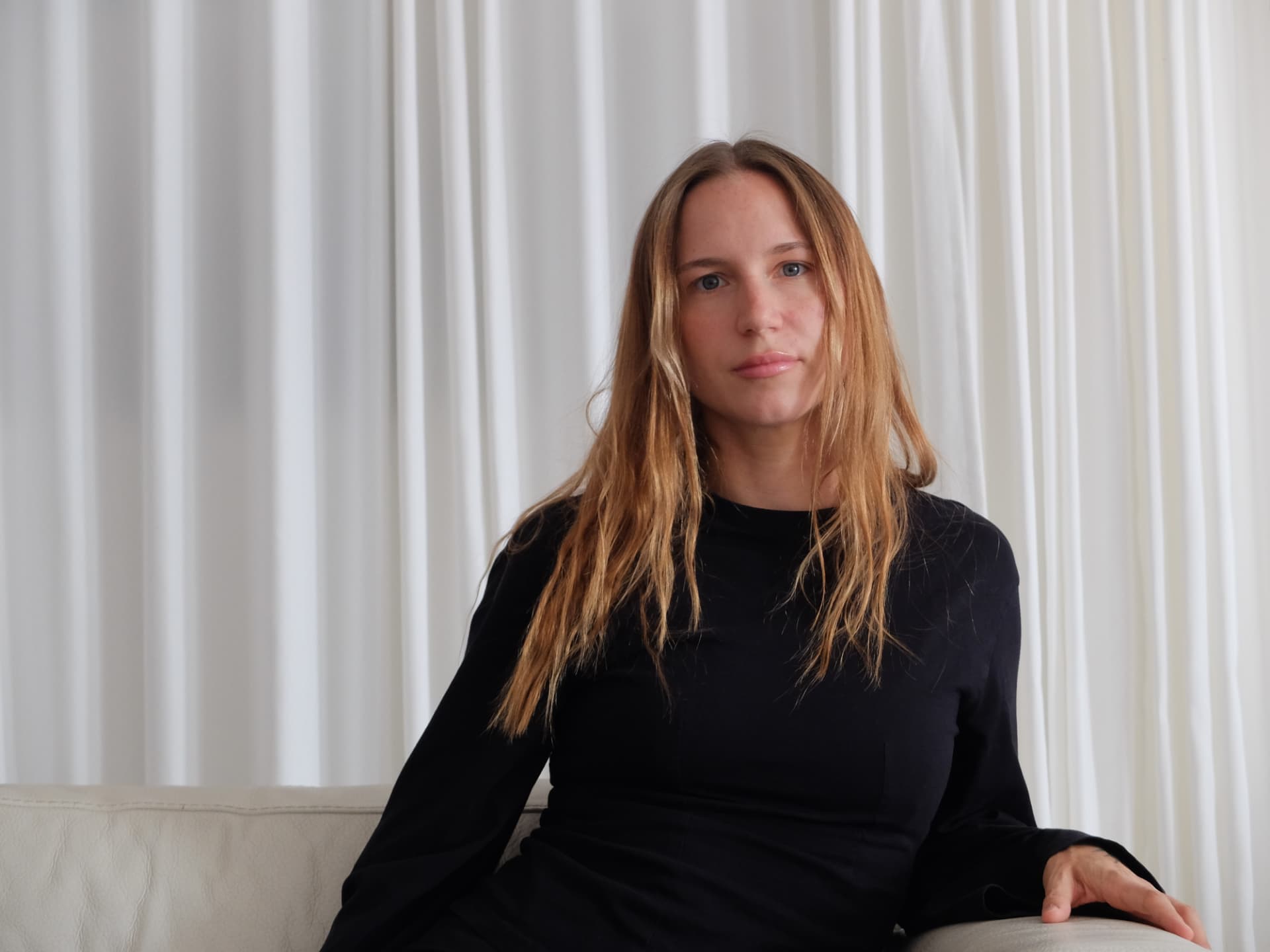 anja seated in front of soft white curtains