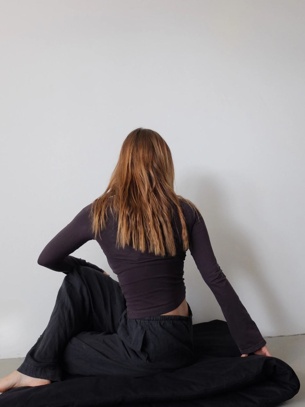 Anja Wittmann seated on the floor seen from behind, in a quiet yoga moment